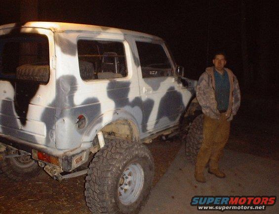 Camouflaged Suzuki Samurai with large tires and a man standing next to it
