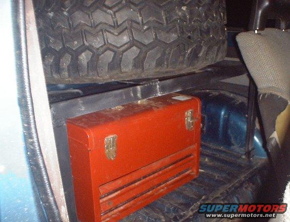 Spare tire and red toolbox in the cargo area of a vehicle