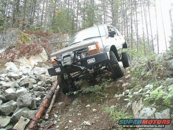 Brown SUV off-roading on a rocky, wooded trail.