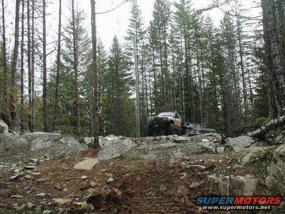 Two off-road vehicles on a rocky trail in a forest.