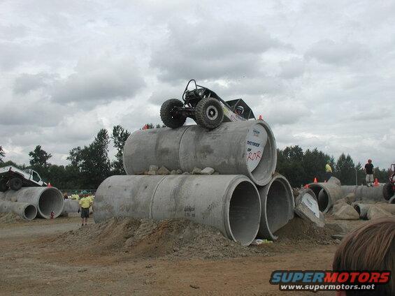 Custom off-road buggy on concrete pipes with another off-road vehicle in the background.