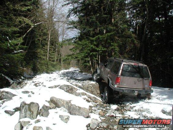 Tan Ford Explorer on a rocky, snow-covered forest trail.