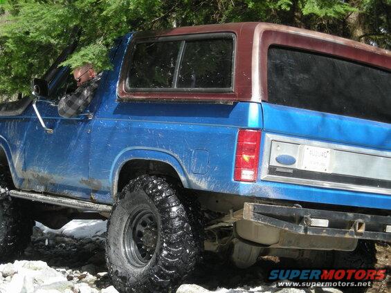 Blue 1985 Ford Bronco off-road with driver visible