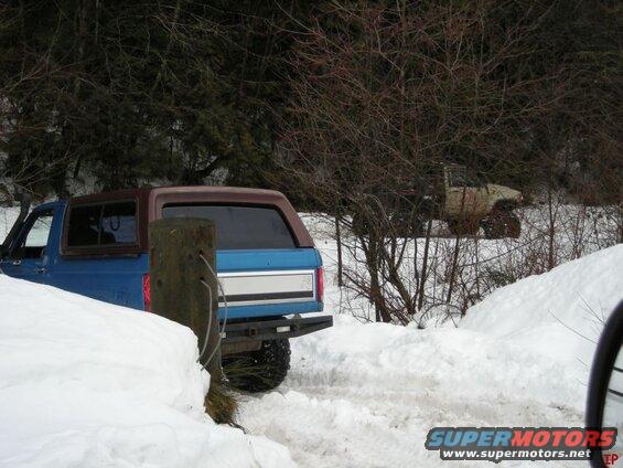 Blue 1985 Ford Bronco in the snow with a brown top.