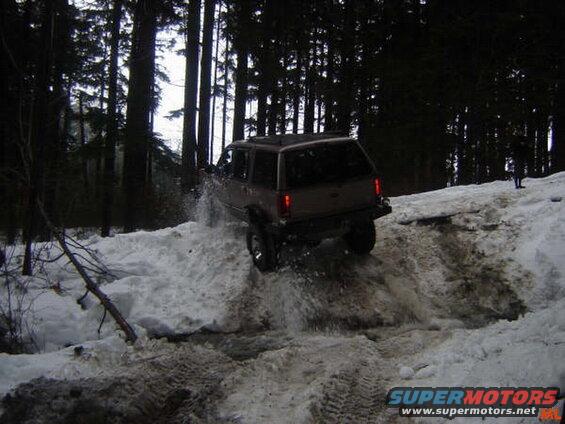 SUV driving through deep snow and slush in a forest