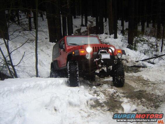 Red Jeep Wrangler driving on a snowy forest road