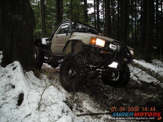 Off-road vehicle with large tires on a snowy forest trail.