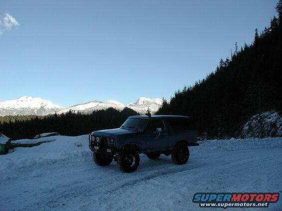 Dark blue Ford Bronco in a snowy mountain landscape.