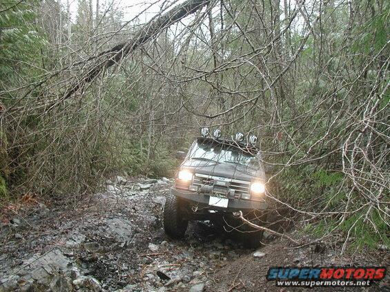 1985 Ford Bronco on a rocky, wooded trail.