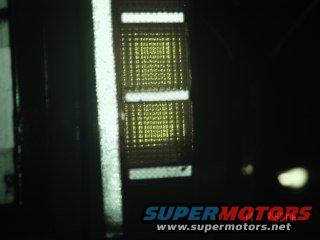Close-up of a yellow and white tail light assembly with SUPERMOTORS.NET text