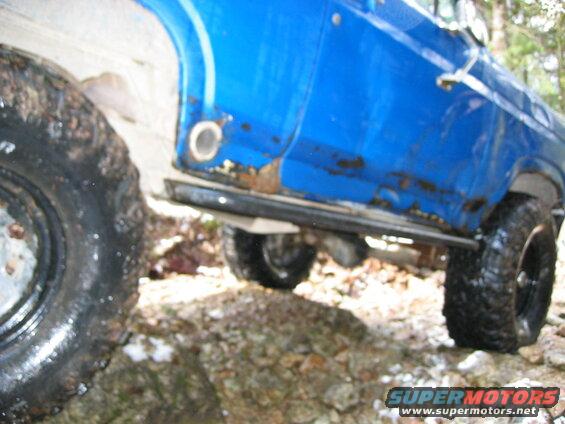 Blue Ford Bronco side view with rust and off-road tires on rocky terrain