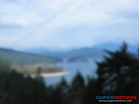 Blurry landscape with water, mountains, and trees.