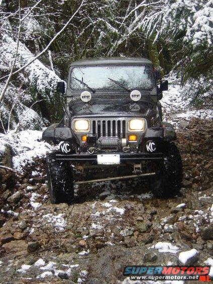 Jeep Wrangler driving on a snowy, rocky trail.