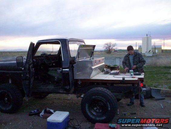 Side view of black pickup truck flatbed with toolbox and person working