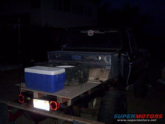 flatbed truck bed at night with a blue cooler and diamond plate toolbox on it