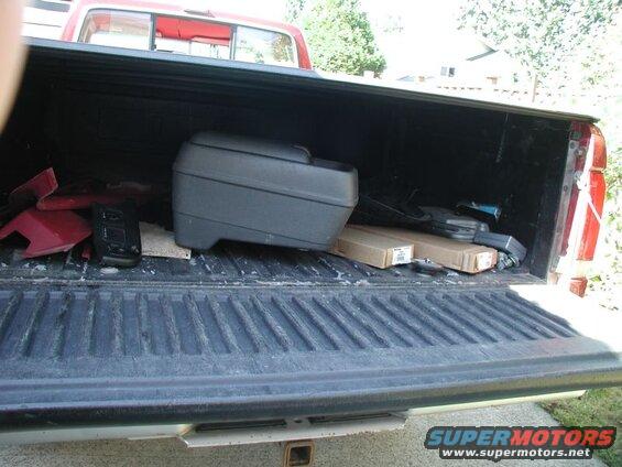 Open tailgate of a red and silver pickup truck bed with cargo.