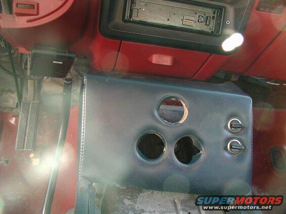 Custom center console with cutouts and toggle switches inside a vehicle.