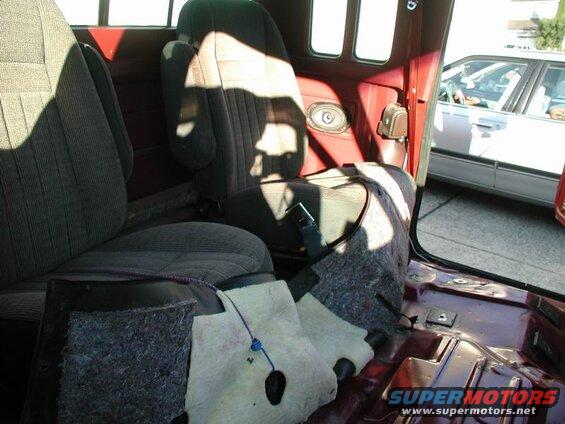 Interior of a red Ford F-250 pickup truck with rear seats removed and sound deadening pulled back.