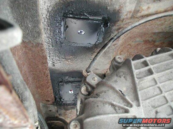 Underside of a vehicle showing reinforcement plates near transmission housing.