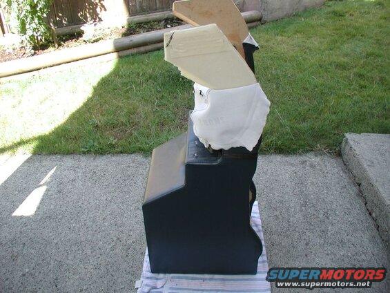 Black upholstered car seat with white padding and tape, outdoors.