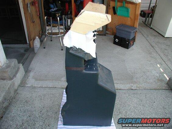 Automotive seat or console, partially covered, outdoors on a driveway.