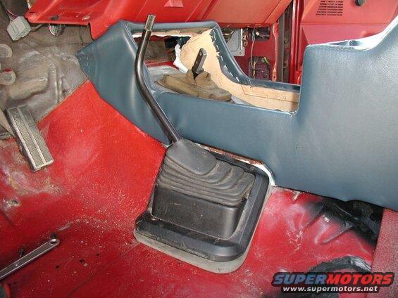 Interior of a vehicle showing a manual transmission shifter and center console.