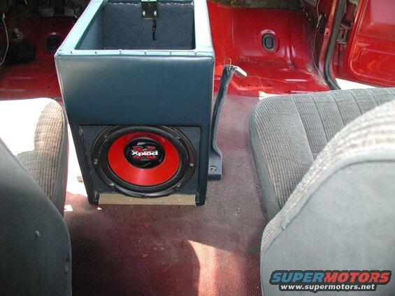 Interior of a red Ford F-250 pickup truck with a custom center console and subwoofer.