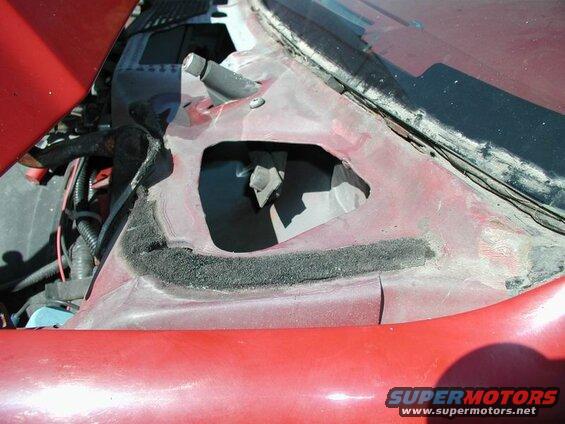 Cowl area of a red vehicle with an opening and visible wiring.
