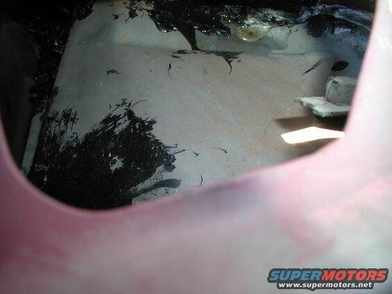 Interior view of a dirty vehicle with black tar-like material and a bolt and washer.