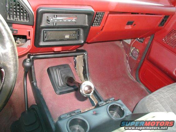 Interior of a red 1990 Ford F-250 pickup truck showing dashboard, shifter, and center console.