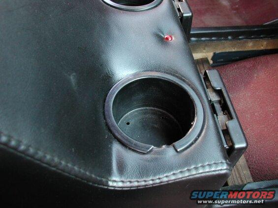 Black vinyl center console with cup holders and a red indicator light.