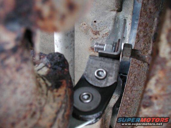 Close-up of a metal bracket with bolts on a rusty vehicle frame.