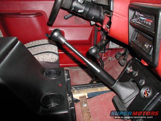 Interior of a pickup truck showing dual gear shifters, cup holders, and dashboard with radio and gauges.