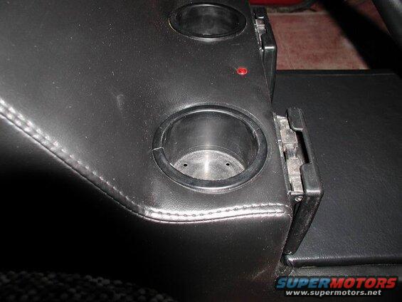 Black vinyl center console with two cup holders and a red light.