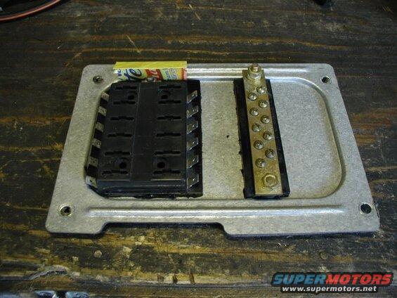 Auxllary fuse panel and ground bar mounted to the right panel that is behind the kick-panel.