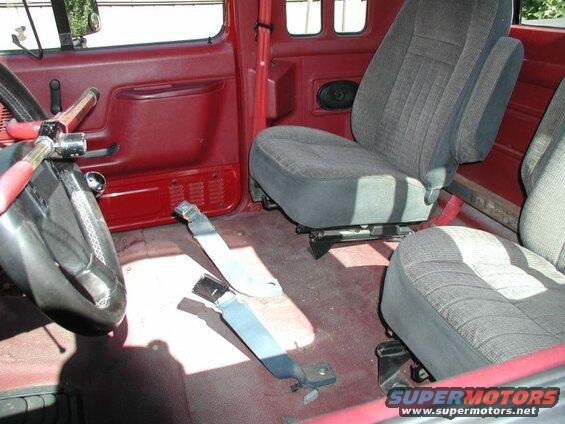 Interior of a red Ford F-250 pickup truck showing driver's side door, steering wheel, and front seats.