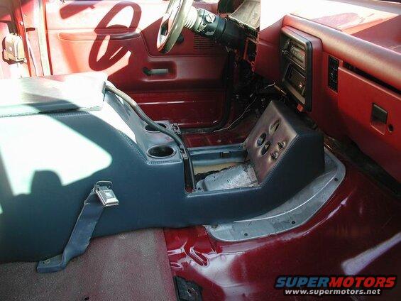 Interior of a red Ford F-250 truck with a dark blue center console and cup holders.