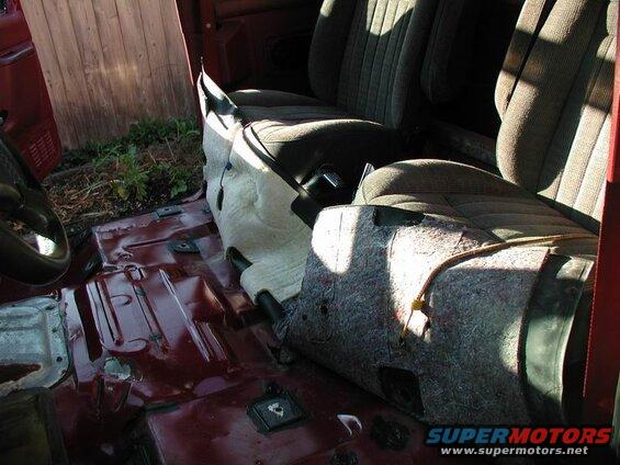 Interior of a vehicle with seats and exposed floor.