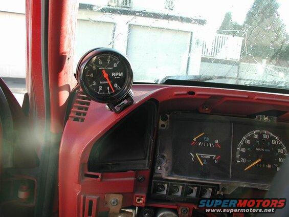 Interior dashboard of a red Ford F-250 with an RPM gauge and speedometer.