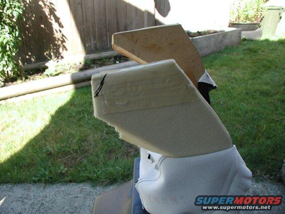 Close-up of beige foam padding taped to a white object, possibly a vehicle part, outdoors.