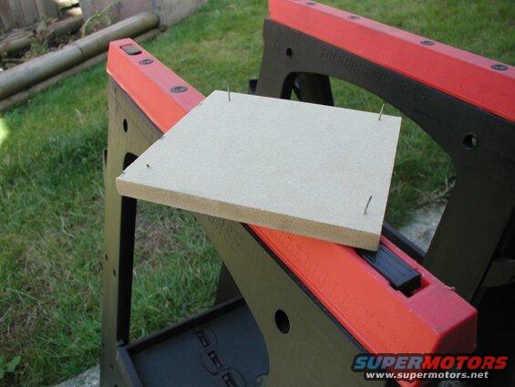 Particle board with nails on a sawhorse