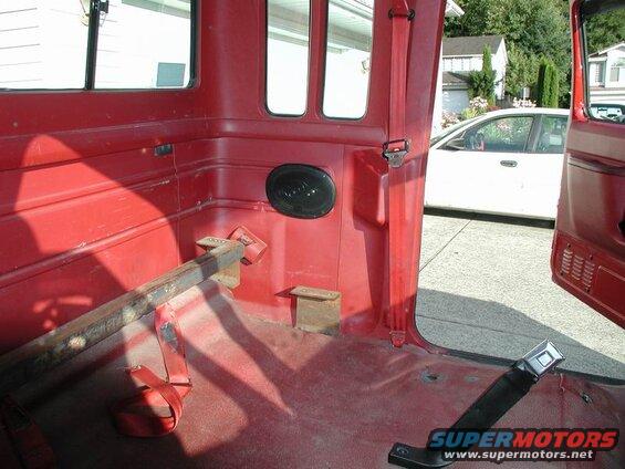 Interior of a red Ford F-250 pickup truck, showing the rear area and a speaker.