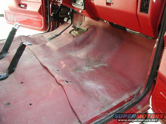 Interior of a red 1990 Ford F-250 showing the driver's side floor and lower dashboard.