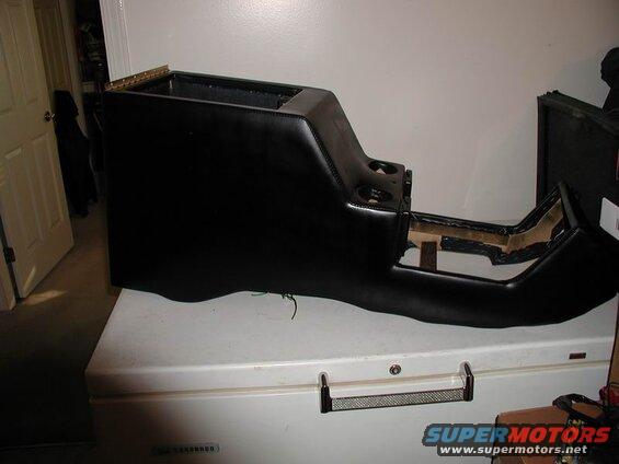 Black custom upholstered center console with cup holders on a white chest freezer.