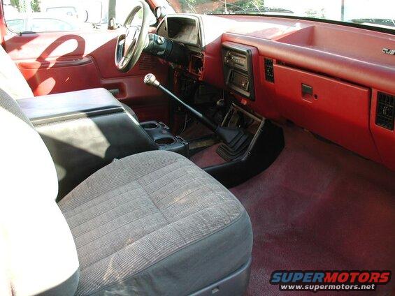 Interior of a red Ford F-250 pickup truck showing driver's seat, center console, and shifter.