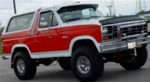 Red and white Ford Bronco with aftermarket visor and hood protector