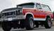 1985 Ford Bronco - This red and white Ford Bronco features a lifted suspension and large off-road tires.