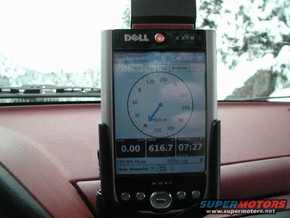 Dell Axim X51v GPS mounted on a car dashboard, showing navigation data with a snowy background.