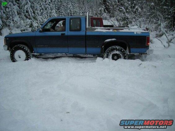 Blue and black pickup truck stuck in deep snow.