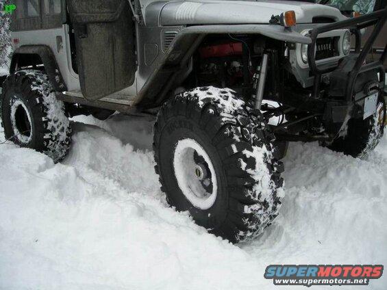 Modified Toyota Land Cruiser with large tires in deep snow.
